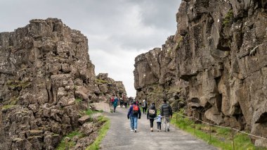 Thingvellir, İzlanda - Ağustos 2019: Tektonik plakalı dereyle Thingvellir Ulusal Parkı boyunca yürüyen turistler