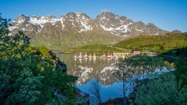 Güzel doğa Norveç doğal manzarası, renkli özel tekneleri olan bir göl üzerinde dağ yansıması.
