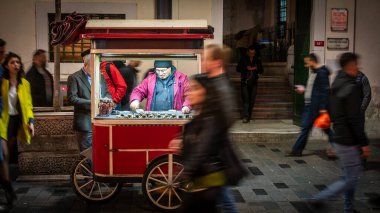 İstanbul, Türkiye - Kasım 2019: Akşam saatlerinde Taksim İstiklal Caddesi 'nde kavrulmuş kestane satan adam. Alan derinliği ve bulanıklaştırma kasıtlı ve orijinal olarak yapılır