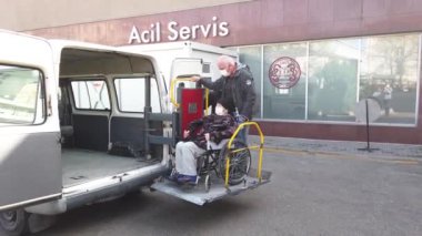 Ankara, Türkiye - Mart 2021: Tekerlekli sandalyedeki sağlık maskeli engelli yaşlı kadın ambulanstan çıkarıldı