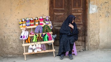 Masuleh, Iran - May 2019: Iranian woman selling hand made dolls for tourists clipart