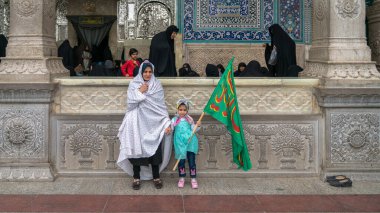 Fatima Masumeh Tapınağı, Qom, İran - Mayıs 2019: İranlı kadınlar ve kızı Qom 'daki Fatima Masumeh Tapınağı içinde bir İslami bayrak taşıyorlar