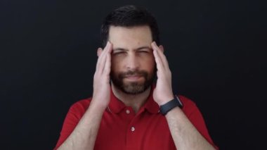 Siyah arka planda izole edilmiş kırmızı tişört giyen bir adam acı çekiyor. Stüdyo çekimi.