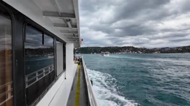 İstanbul, Türkiye - 15 Ekim 2025: İstanbul, Türkiye 'de İstanbul' da feribot güvertesi üzerinden kıyı kenti ve bulutlu gökyüzü altındaki tepelerden görüntüler