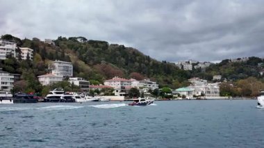 İstanbul, Türkiye - 15 Ekim 2025: İstanbul, Türkiye 'de İstanbul Boğazı kıyı şeridi boyunca lüks liman köşkleri ve yatlar bulutlu gökyüzü altında