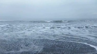 Sakin Dalgalar Bulutlu bir günde Kumsala yuvarlanıyor
