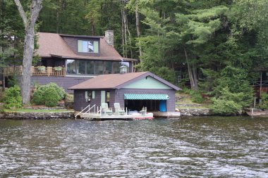 Motorlu tekne dağlardaki bir gölde kayıkhanenin altında demirlemiş.