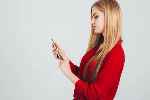 Dívka v červené košili pomocí smartphonu — Stock fotografie