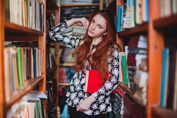 Unga rödhårig flicka i biblioteket — Stockfoto
