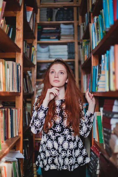Νέοι κοκκινομάλλα κοπέλα σε βιβλιοθήκη — Φωτογραφία Αρχείου
