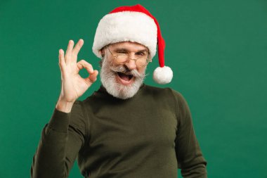 Mutlu sakallı, modern Noel Baba yeşil arka planda iyi görünüyor.