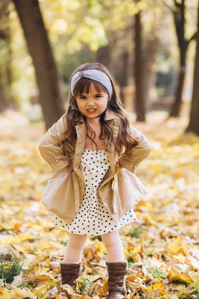 穿着米黄色外套的漂亮小女孩在秋天的公园里怒气冲冲 — 图库照片
