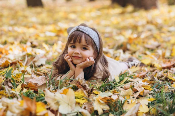 Счастливая Красивая Маленькая Девочка Бежевом Пальто Лежит Среди Желтых Листьев — стоковое фото