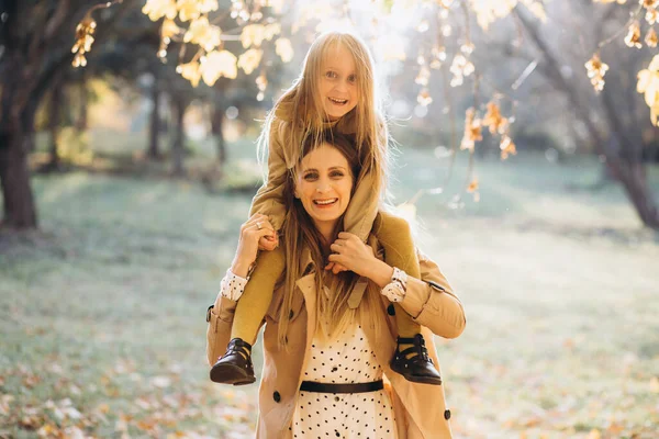幸せな母親と彼女の美しい娘は楽しみを持っており 秋の公園を歩く — ストック写真