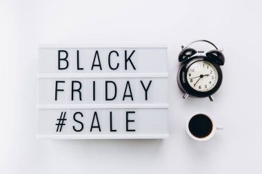 Creative Top view düz promosyon kompozisyonu bir fincan kahve, çalar saat ve aydınlatma kutusu beyaz arkaplan kopyalama alanı üzerinde Kara Cuma satış metni ile yatıyordu