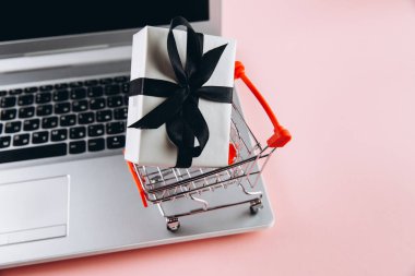 Kara Cuma konsepti. Kırmızı tramvay hediye ve pembe arka planda dizüstü bilgisayar.