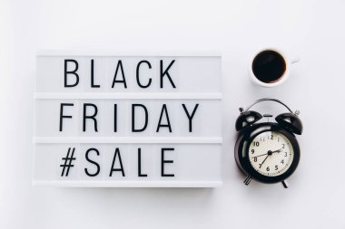 Creative Top view düz promosyon kompozisyonu bir fincan kahve, çalar saat ve aydınlatma kutusu beyaz arkaplan kopyalama alanı üzerinde Kara Cuma satış metni ile yatıyordu