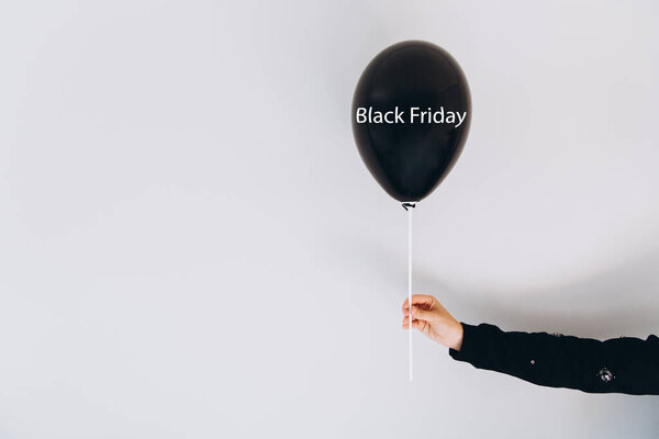 Женская рука держит воздушный шар с надписью Черная пятница на сером фоне стены