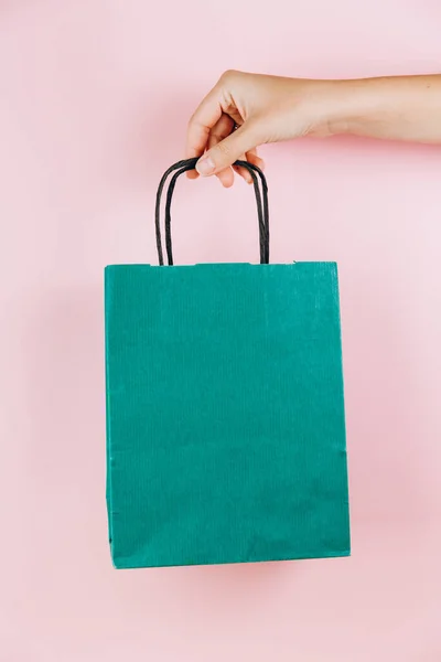 ピンク地に緑の紙袋を持つ女性の手 — ストック写真