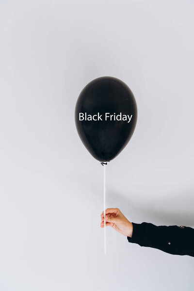 Женская рука держит воздушный шар с надписью Черная пятница на сером фоне стены