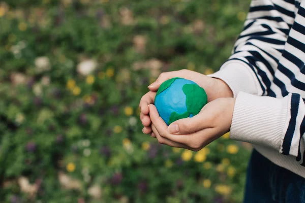 stock image Female hands holding Earth in hands against green spring background.