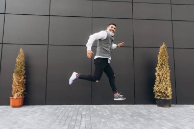 Keskin sakallı, kır saçlı, yaşlı bir adam şehrin temiz alanlarına atlıyor.