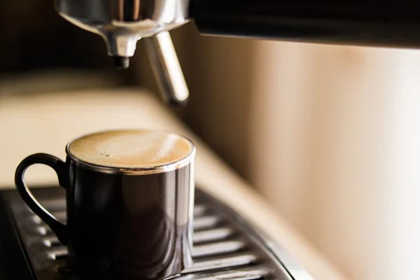 Cafetera espresso haciendo café y vertiendo en una taza marrón — Foto de Stock