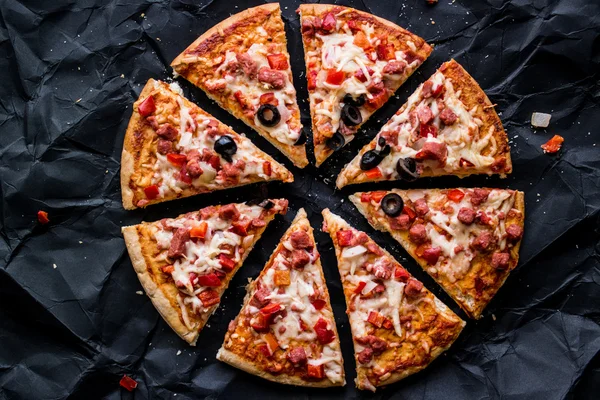 Pizza slices with potato wedges , nuggets and beverage on a black surface