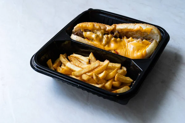 Take Away Philly Cheese Steak Sandwich with Melted Cheddar Cheese and Potatoes in Plastic Container Plate Package. Ready to Eat