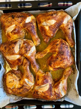 Fırın tepsisinde fırın kağıdıyla pişirilmiş tavuk budu. Hizmet ve Yemeye Hazır.