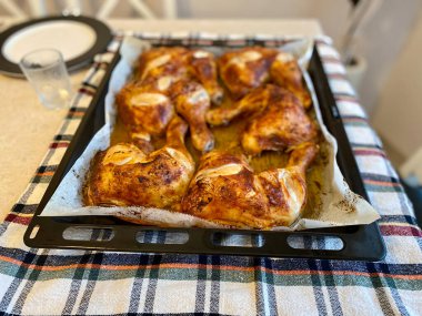 Fırın tepsisinde fırın kağıdıyla pişirilmiş tavuk budu. Hizmet ve Yemeye Hazır.