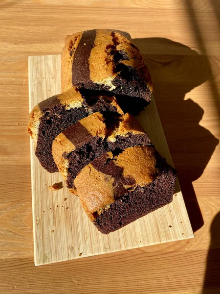 Homemade Whole Sliced Zebra Cake with Chocolate on Wooden Board and Direct Natural Sunlight. Ready to Serve and Eat.