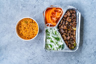 Tablo folyo tabağında soğan ve domatesli Türk Karaciğeri Götürün. Bulghur ya da Bulgur Rice Pilav Pilaf ile servis edilmiş. Yemeye hazır..