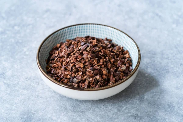 Chocolate Cacao Nibs or Cocoa Nibs in Bowl Ready to Use on Dark Wooden Surface. Ready to Eat.