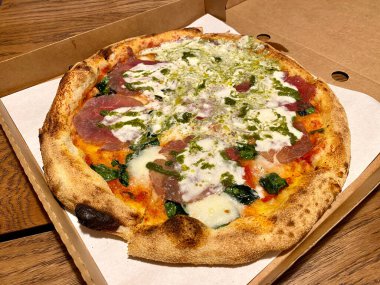 Pesto soslu pizza ve tahta yüzeyde Stracciatella peyniri. Yemeye hazır..