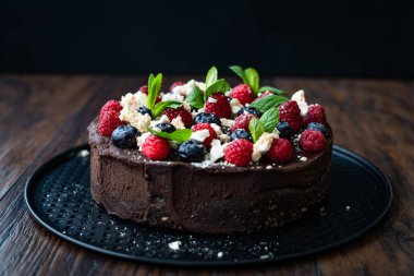 Ahududulu çikolatalı çiğ kek, yaban mersini, krema ve nane yaprağı. Yemek ve Servis İçin Hazır.