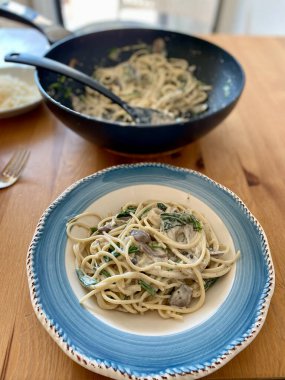 Wok ile Tahta Masa üzerinde ev yapımı kremalı mantarlı spagetti. Yemeye hazır..