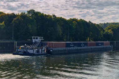 Scharnebeck, Almanya; 30 Eylül 2025: Sch 2334 numaralı itfaiye teknesinin Elbe-Seitenkanal 'da bir yük mavnasını çekişi, nakliye ve seyrüsefer görüntüsü.