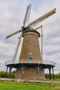 Neede, Hollanda; 14 Ekim 2025: Hollanda 'nın mirasının bir sembolü olarak bulutlu sonbahar gökyüzü altında yakalanan yuvarlak tuğlalı yel değirmeni De Hollandsche Molen 1925 kasırgasından sonra yeniden inşa edildi..