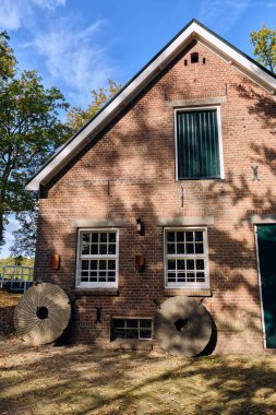 Apeldoorn, Hollanda; 18 Ekim 2025: Apeldoorn yakınlarındaki tarihi Wenumse su değirmeni, aşırı gelişmiş su tekeri, tuğla cephesi ve sonbahar manzarasında değirmen taşları olan geleneksel Hollanda mısır değirmeni.