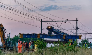 Hoogeveen, Hollanda; 11 Haziran 2023: Demiryolu müteahhitleri Zwolle Groningen hattına akşam inşaatı sırasında ağır vinçle yeni bir hızlı demiryolu şalteri kurdular.