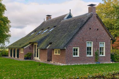 Norg, Hollanda; 9 Ekim 2025: Norg 'un kırsal kesimlerinde sazdan çatı ve kırmızı tuğla duvarlarla yenilenmiş çiftlik evi, geleneksel mimari ve kırsal yaşamı gösteriyor.