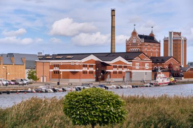 Ahus, İsveç 22 Eylül 2025: Mutlak Votka damıtma binaları ve sahil boyundaki Spiritkyrkan kulesi İsveç mirası endüstrisini ve modern liman faaliyetlerini gösteriyor.