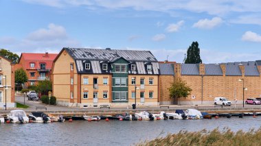 Ahus, İsveç 22 Eylül 2025: Gamla Skeppsbron boyunca uzanan tarihi depo cephesi İsveç kıyı mirası ve geleneksel kıyı mimarisini gösteren sakin liman suyuna yansıdı.