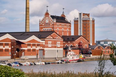 Ahus, İsveç 22 Eylül 2025: Mutlak Votka damıtma binaları ve sahil boyundaki Spiritkyrkan kulesi İsveç mirası endüstrisini ve modern liman faaliyetlerini gösteriyor.
