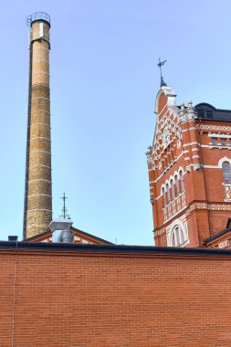 Ahus, İsveç - 22 Eylül 2025: Absolut Votka fabrikasındaki sanayi ayrıntılarına yakından bakın tuğla mimari boru tesisleri ve tarihi liman rıhtımındaki Spiritkyrkan kulesi.