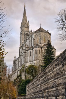Fransa 'da kule ve taş duvarlı Lourdes Sığınak Bazilikası mimarisinin dış görünüşü. Bu dini mekan popüler bir seyahat merkezi ve Avrupa katedrali..