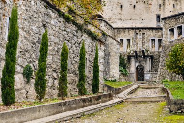 Fransa 'daki Chateau Fort de Lourdes' in girişinde taş duvarlar ve yeşil ağaçlar var. Pireneler Dağları 'ndaki bu tarihi dönüm noktası popüler bir turizm merkezidir..