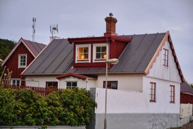 İsveç 'in Öresund kıyısı boyunca Helsingborg' a yakın Lard 'daki deniz kıyısındaki evlerde kırmızı ve beyaz binalar ve çitlerle çevrili bir İsveç köyünün özünü yansıtan görüntüler sergileniyor..