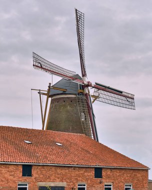 Gapinge Zeeland Hollanda 'daki Windmill De Graanhalm Graanhalm Tahıl Sapı' nın önü tuğla bir bina ve kırmızı kiremit kaplı bir çatısı var. Bu Hollanda kırsal kesiminde geleneksel mimari ve kültür mirası sergileniyor.